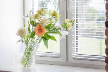 Pencere kenarındaki cam vazoda yaz çiçekleri
