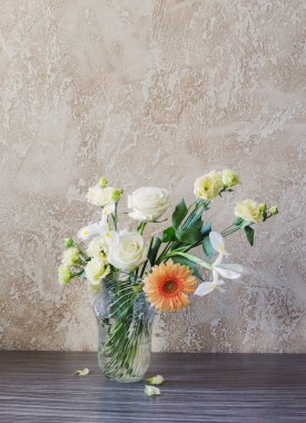 Arka plandaki masada cam vazoda bir buket.