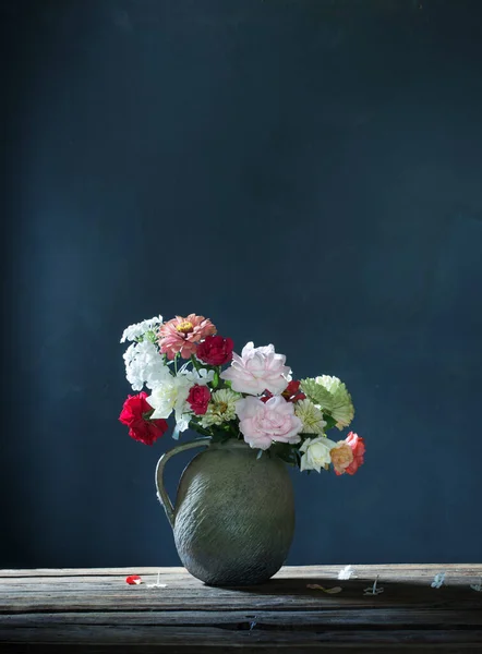 蓝色背景的木制桌子上陶瓷壶中的夏花 — 图库照片