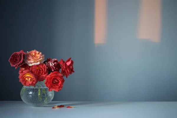 蓝色底色玻璃瓶中的红玫瑰 — 图库照片