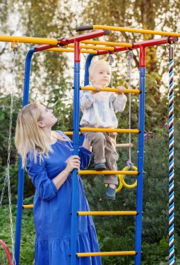 Küçük çocuk ve annesi yaz günü oyun parkında.