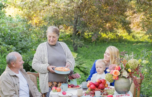 快乐的家庭在花园里摆满苹果派的餐桌旁 — 图库照片