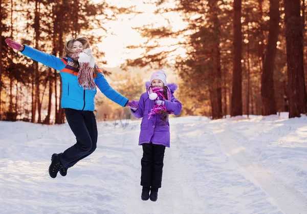 Madre y niña saltando en el bosque de invierno — Foto de Stock