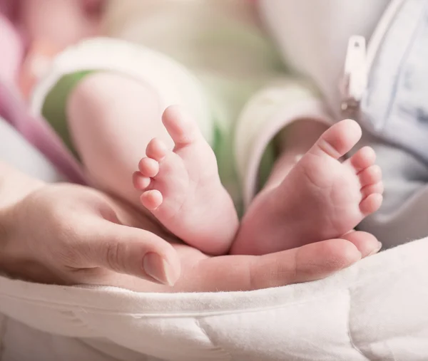 Bebé pies en la mano madre — Foto de Stock