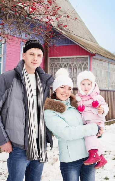 Beautiful family in warm clothes standing  of his house in winte — Stock Photo, Image