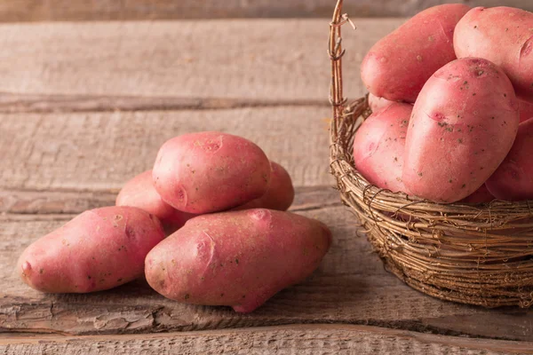 Mand met rode aardappelen op houten achtergrond — Stockfoto