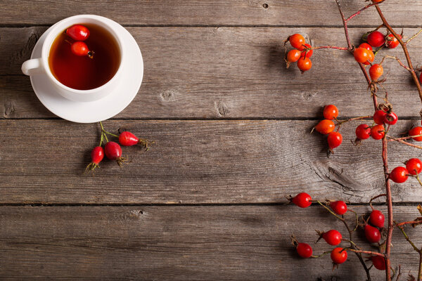 cup of tea with hip roses, on wooden table