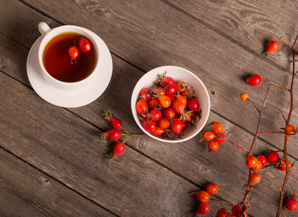cup of tea with hip roses, on wooden table