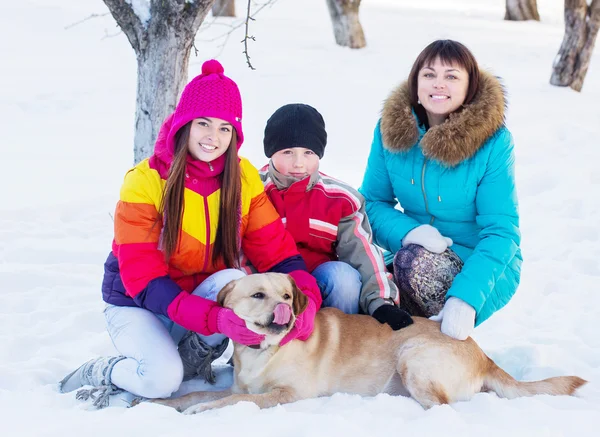 Familj med hund i en snöig trädgård — Stockfoto