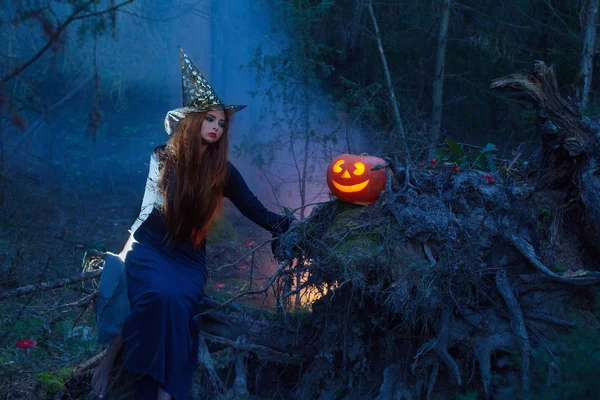 Belle sorcière avec une citrouille dans la forêt magique — Photo