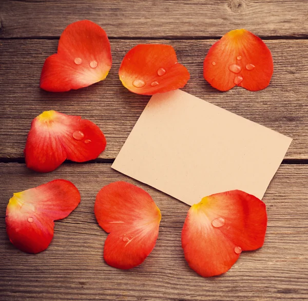 Red petal with paper on wooden background — Stock Photo, Image