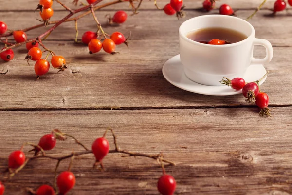 Tasse Tee mit Hüftrosen, auf Holztisch — Stockfoto