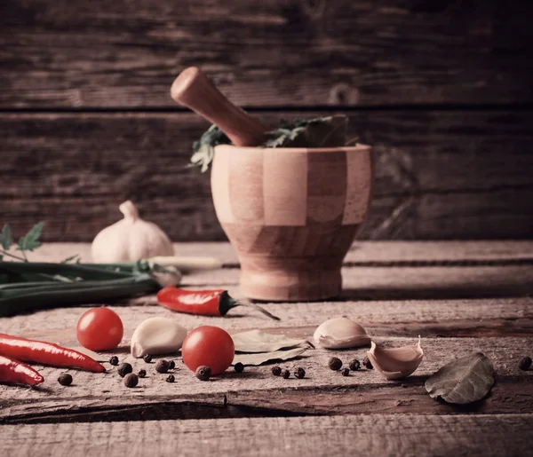Mortaio e pestello con pepe e spezie sul tavolo di legno — Foto Stock