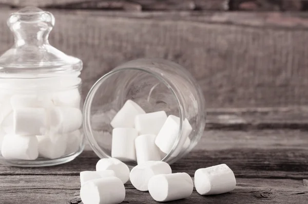 White marshmallows spilling from a jar on wooden background — Stock Photo, Image