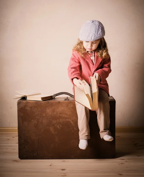 Bambino piccolo con libro sulla valigia al coperto — Foto Stock