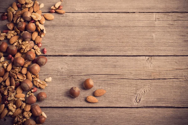 Mixed nuts on old wooden background — Stock Photo, Image