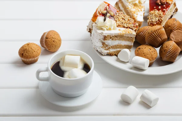 Café avec guimauve et gâteau sur fond de bois blanc — Photo