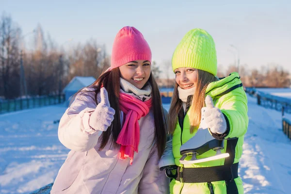 Twee mooie meisjes dragen van warme winterkleren schaatsen — Stockfoto