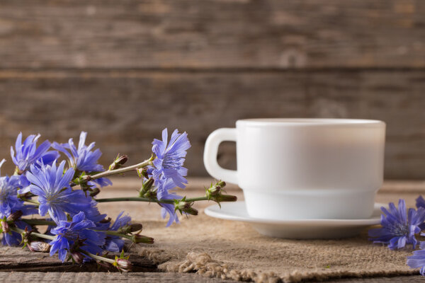 Cup of tea with chicory on wooden background