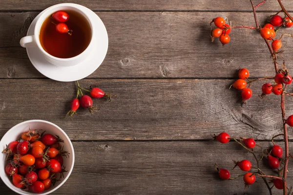 Cup of tea with hip roses, on wooden table — Stock Photo, Image