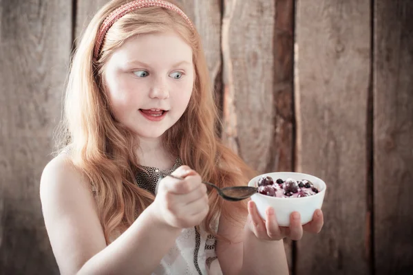 Gelukkig meisje met dessert op houten achtergrond — Stockfoto