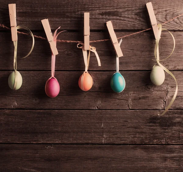 Oeufs de Pâques attacher à la corde avec des épingles à linge sur le backgroun en bois — Photo