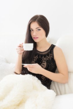 bir fincan kahve ile yatakta çekici genç kadın