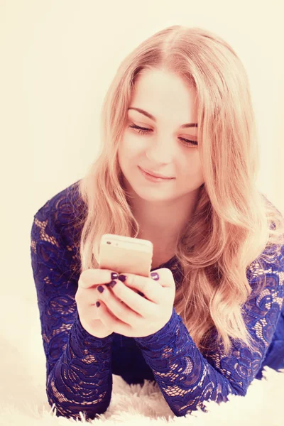 Jonge vrouw liggend op een vloer met telefoon — Stockfoto