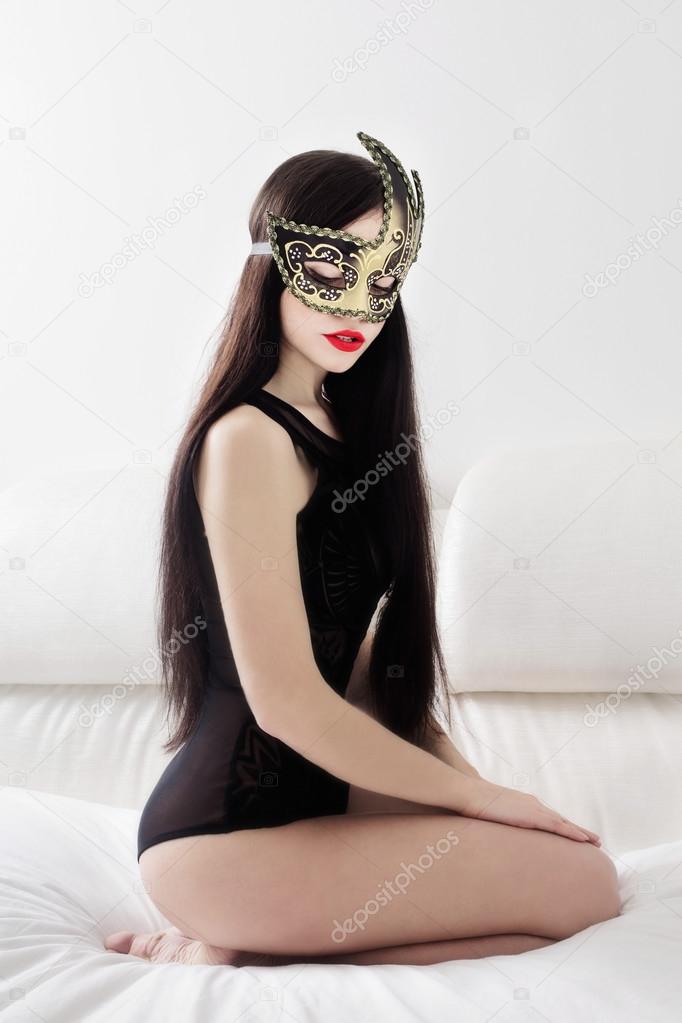girl in mask kneeling on white bed