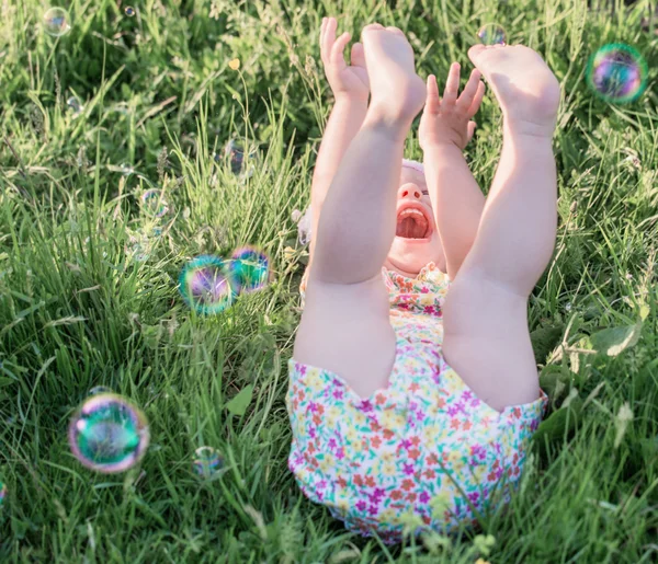 Criança feliz com bolhas de sabão ao ar livre — Fotografia de Stock