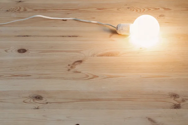 Light bulb lamp on wooden floor — Stock Photo, Image