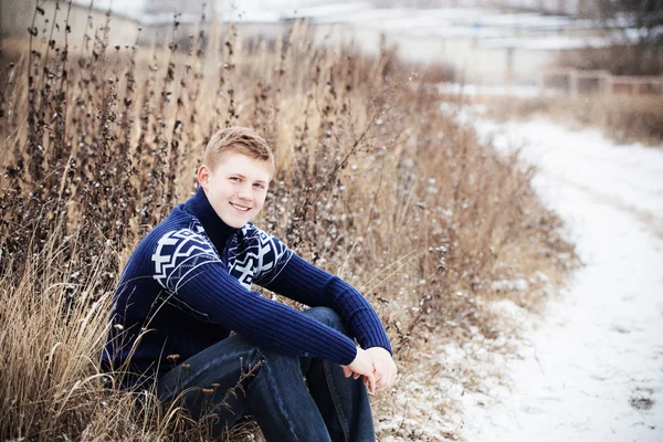 Junge sitzt auf winterlicher Straße — Stockfoto