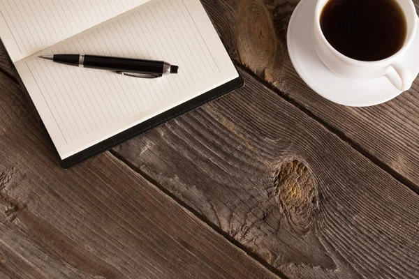 Notebook with pen and coffee  on old  wooden table — Stock Photo, Image