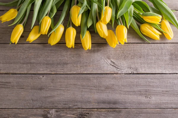 Yellow tulips over wooden table background — Stock Photo, Image