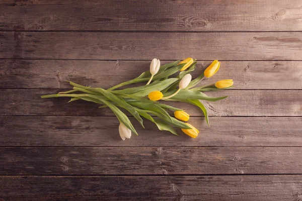 Žluté tulipány dřevěný stůl pozadí — Stock fotografie