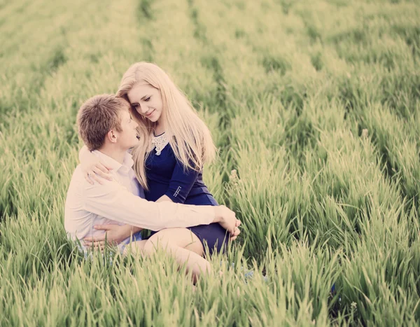 若いカップルが緑の草の上に座り — ストック写真