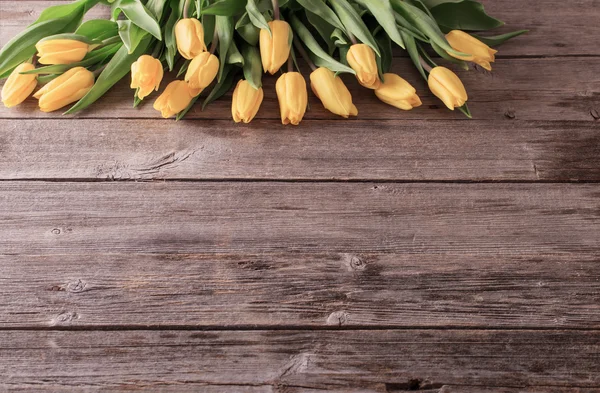 Žluté tulipány dřevěný stůl pozadí — Stock fotografie
