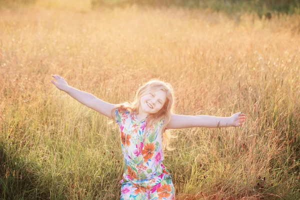 Heureux blond fille sur prairie au coucher du soleil — Photo