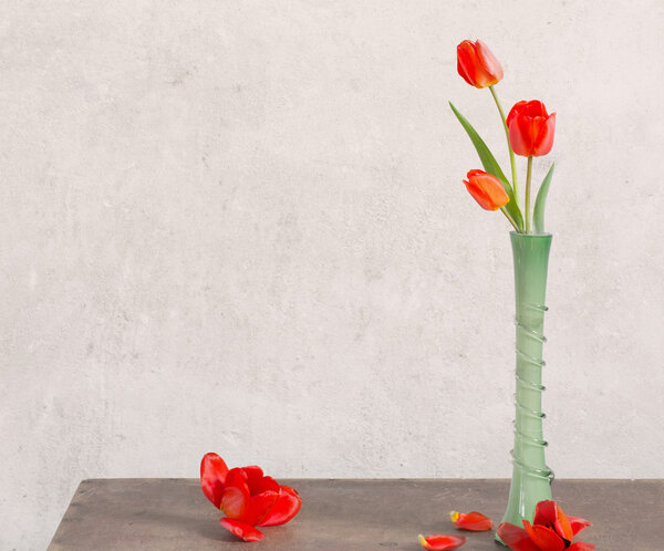 red tulips in green vase on wooden table