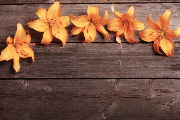 Oranžové lilie na dřevěné pozadí — Stock fotografie