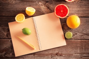 eski ahşap masa üstünde defter ile narenciye