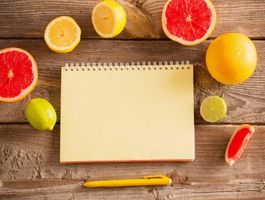 eski ahşap masa üstünde defter ile narenciye