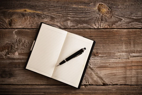 Notebook with pen on old wooden table — Stock Photo, Image