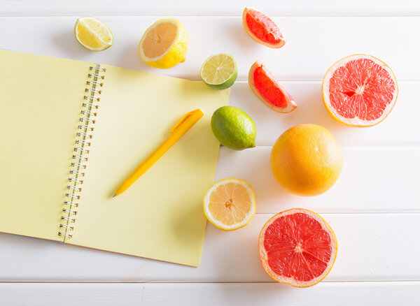 Цитрусовые с ноутбуком на белом деревянном столе
