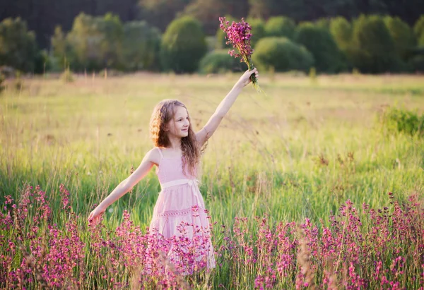 Menina bonita com flores rosa no prado — Fotografia de Stock