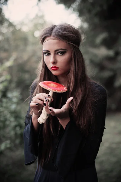 Beautiful witch holding a mushroom — Stock Photo, Image