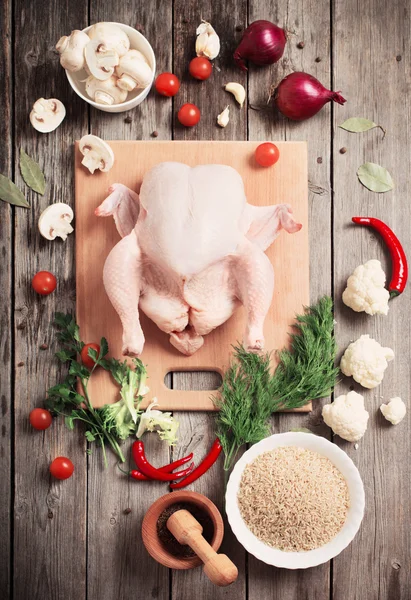 Frango cru inteiro em uma mesa de madeira — Fotografia de Stock