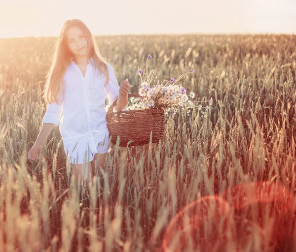Niña en el campo de trigo con cesta de flores —  Fotos de Stock