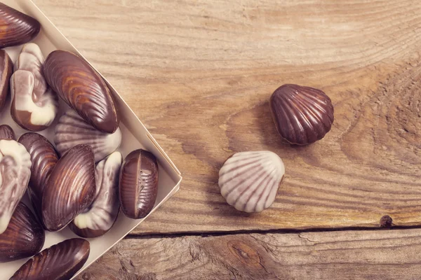 Coquilles de chocolat sur fond en bois — Photo