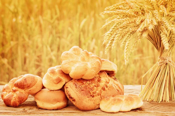 Pão e trigo na mesa de madeira no campo de outono — Fotografia de Stock